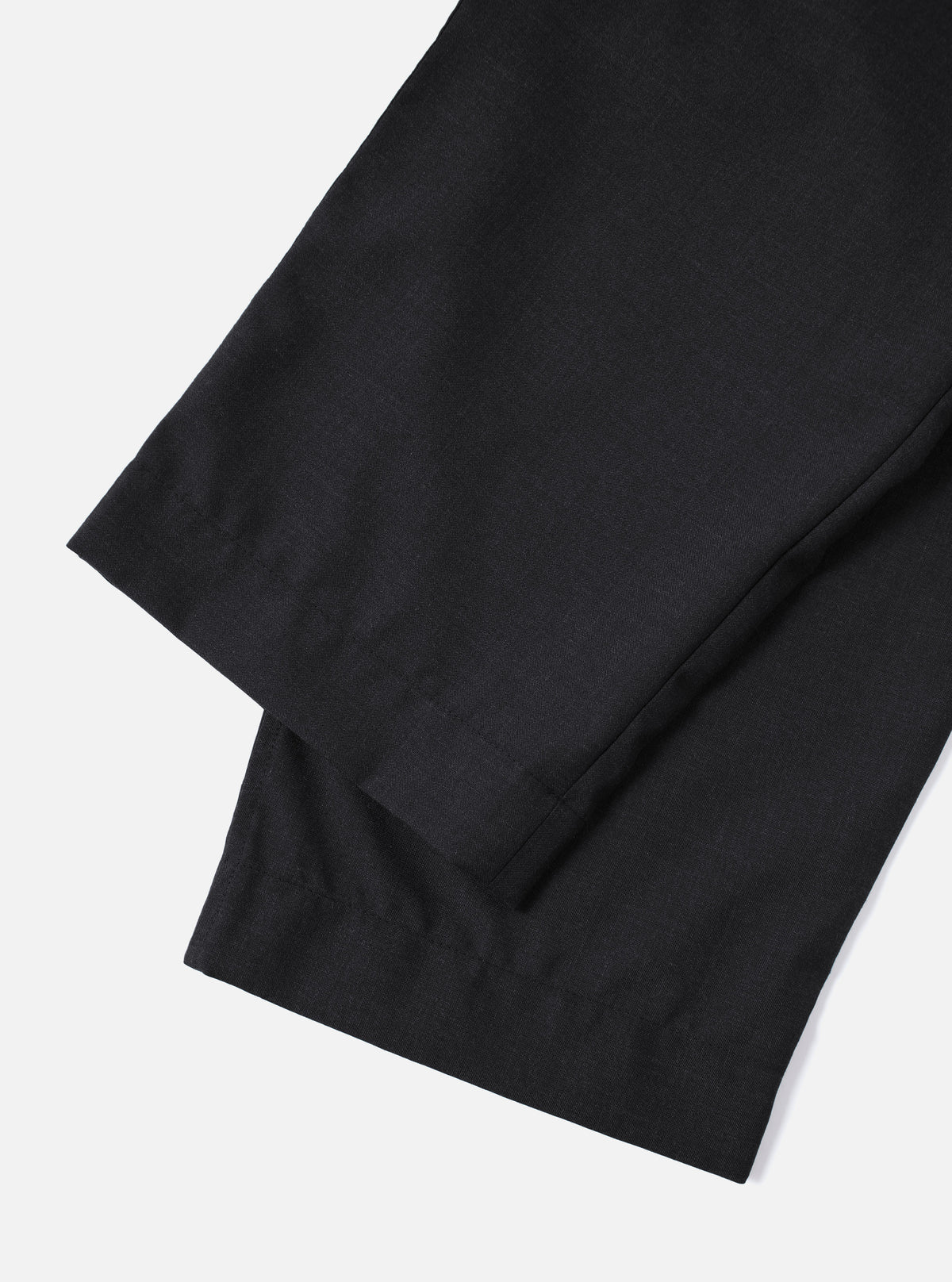 Close-up of the Charcoal Tropical Suiting Oxford Pant on a white background. The dark, tailored trousers are neatly folded, showcasing the fabric and fit.