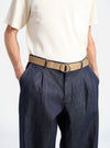 A model wears a Dark Sand Canvas O Ring Belt with dark denim pants against a white background. The belt is canvas with a silver O-ring buckle.