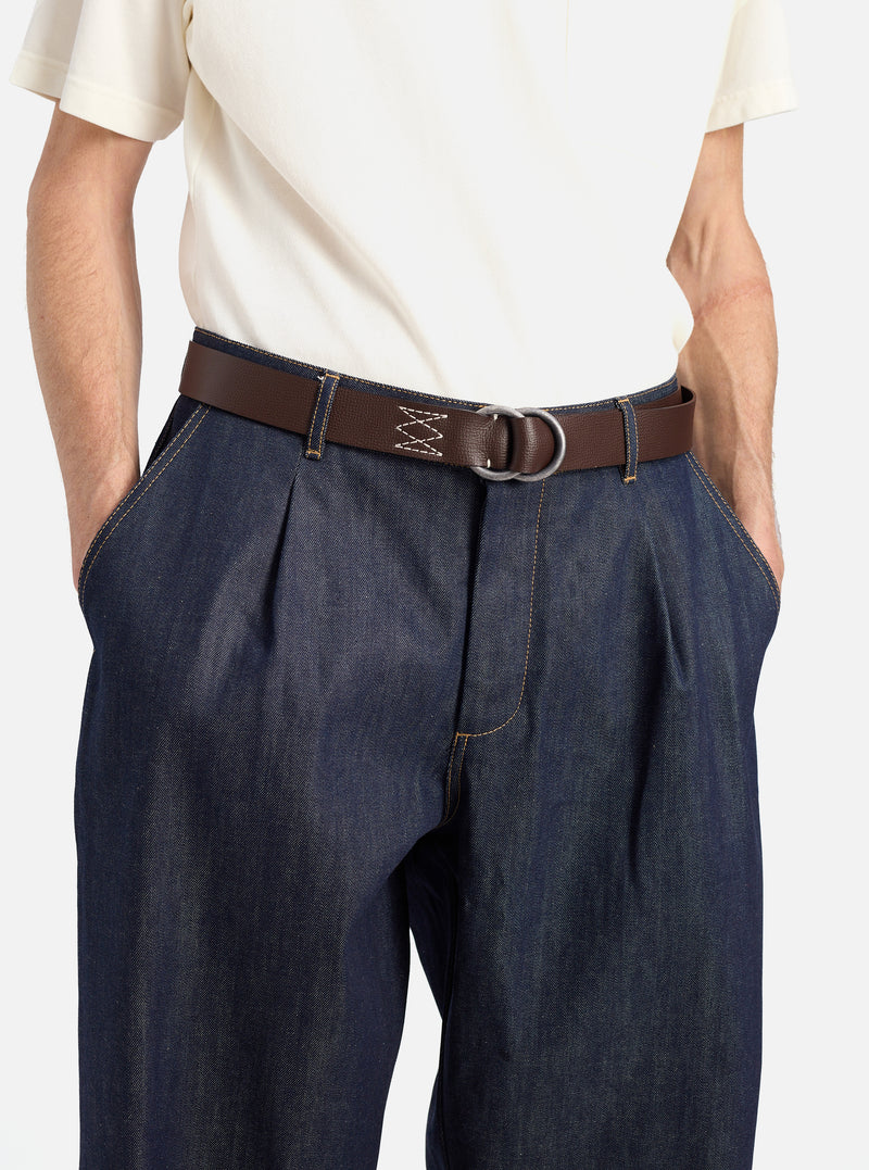 A model wears a Brown Leather O Ring Belt with dark denim pants and a cream shirt against a white background. The belt is brown leather with a silver O ring buckle.