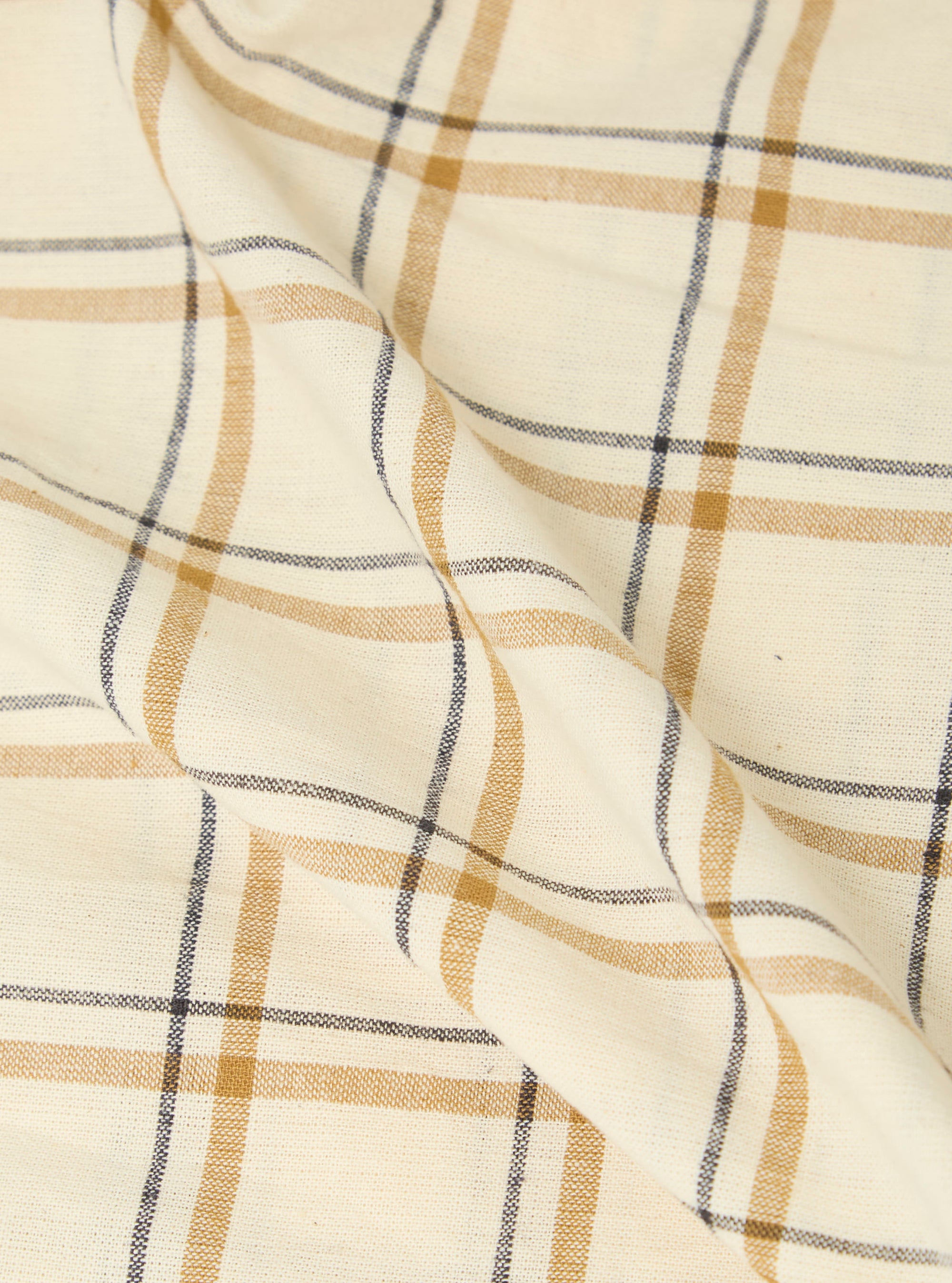 Close-up of the Multi PJ Plaid 3 Pack Boxer Short fabric. The material is a light cream color with gold and navy plaid lines. The fabric is folded on a white surface.