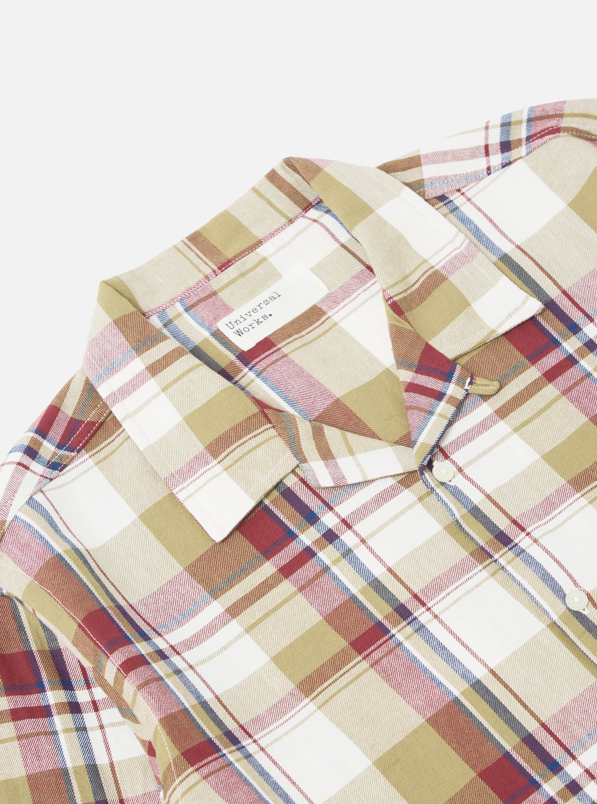 Close-up of the Red/Brown Kip Check Long Pyjama Set. The cotton fabric features a red, brown, and blue plaid pattern on a white background. The set is neatly folded on a white surface.