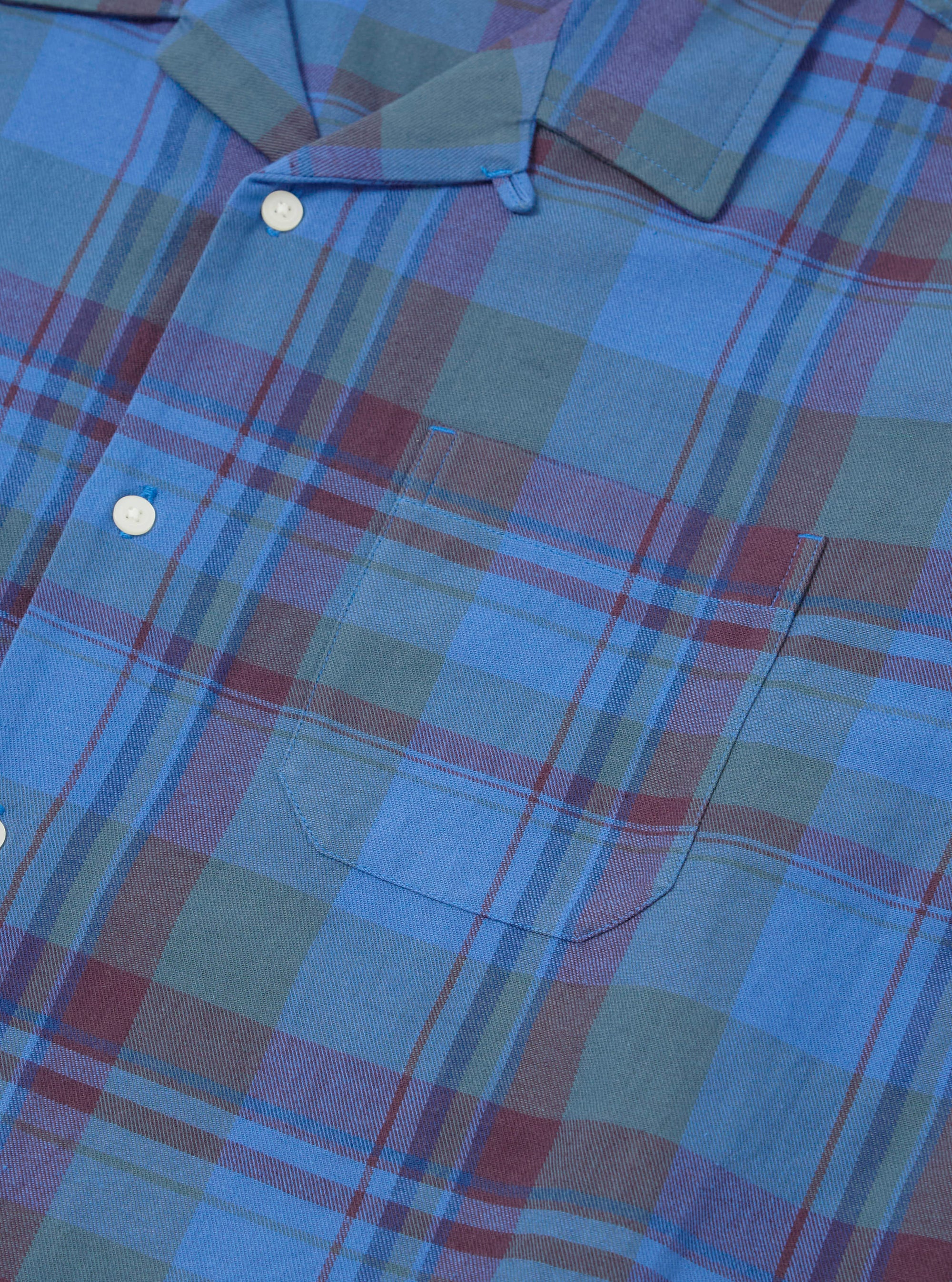 Close-up of the Blue Kip Check Long Pyjama Set. The blue, green, and maroon plaid fabric has white buttons and a pocket. The set is neatly laid out on a flat surface.