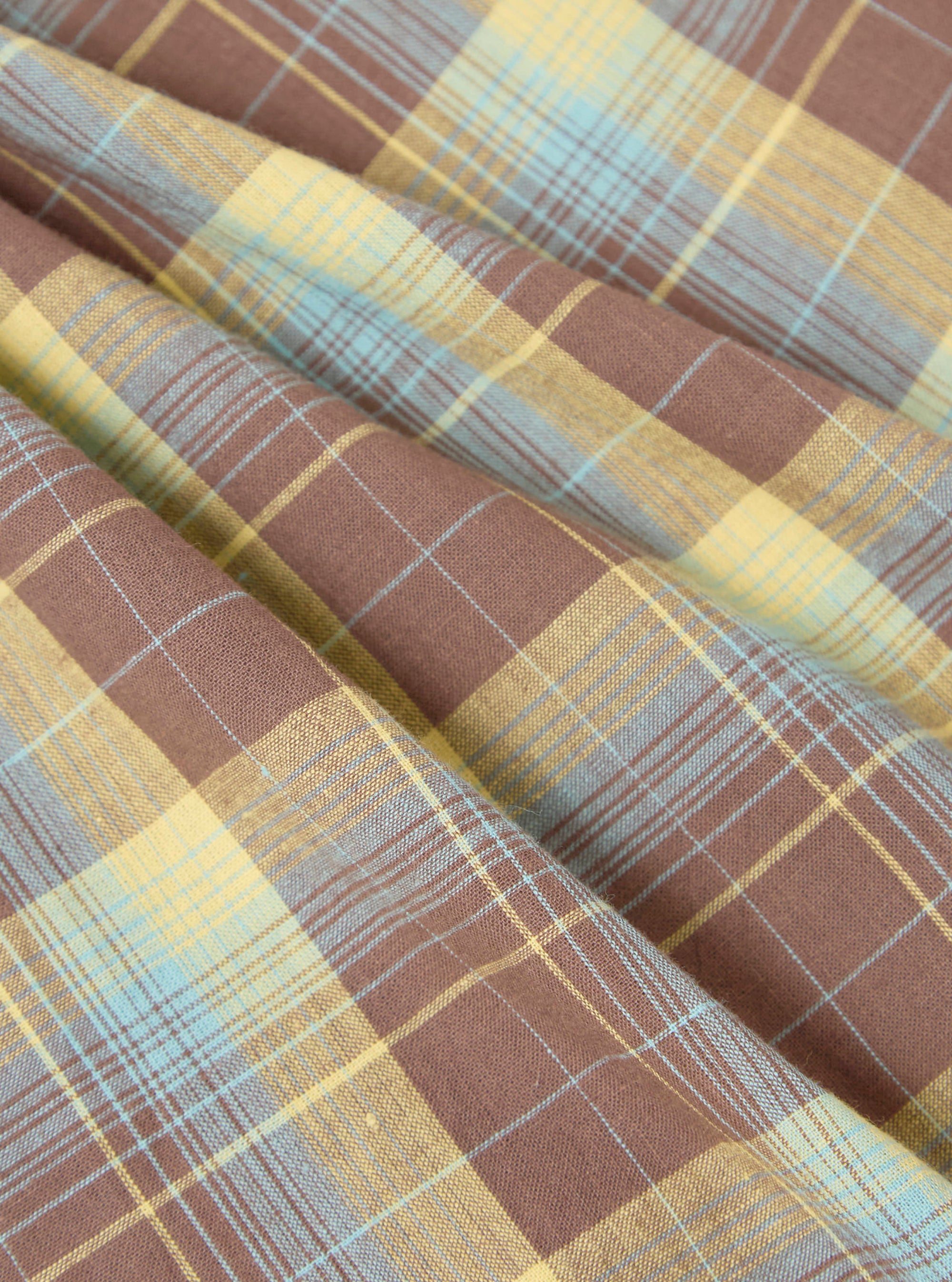 Close-up of the Yellow/Brown Check Pyjama Pant fabric. The pattern features yellow, brown, and blue checks. The fabric is folded, showing texture.