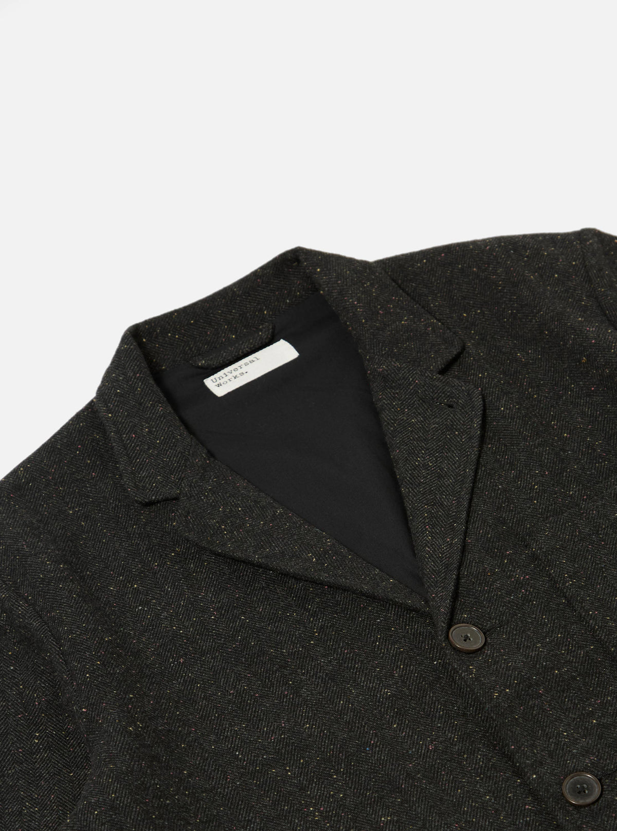 Close-up of the Black Salt N Pepper Tweed Three Button Jacket on a white background. The tweed material has flecks of color. The jacket has a black lining.