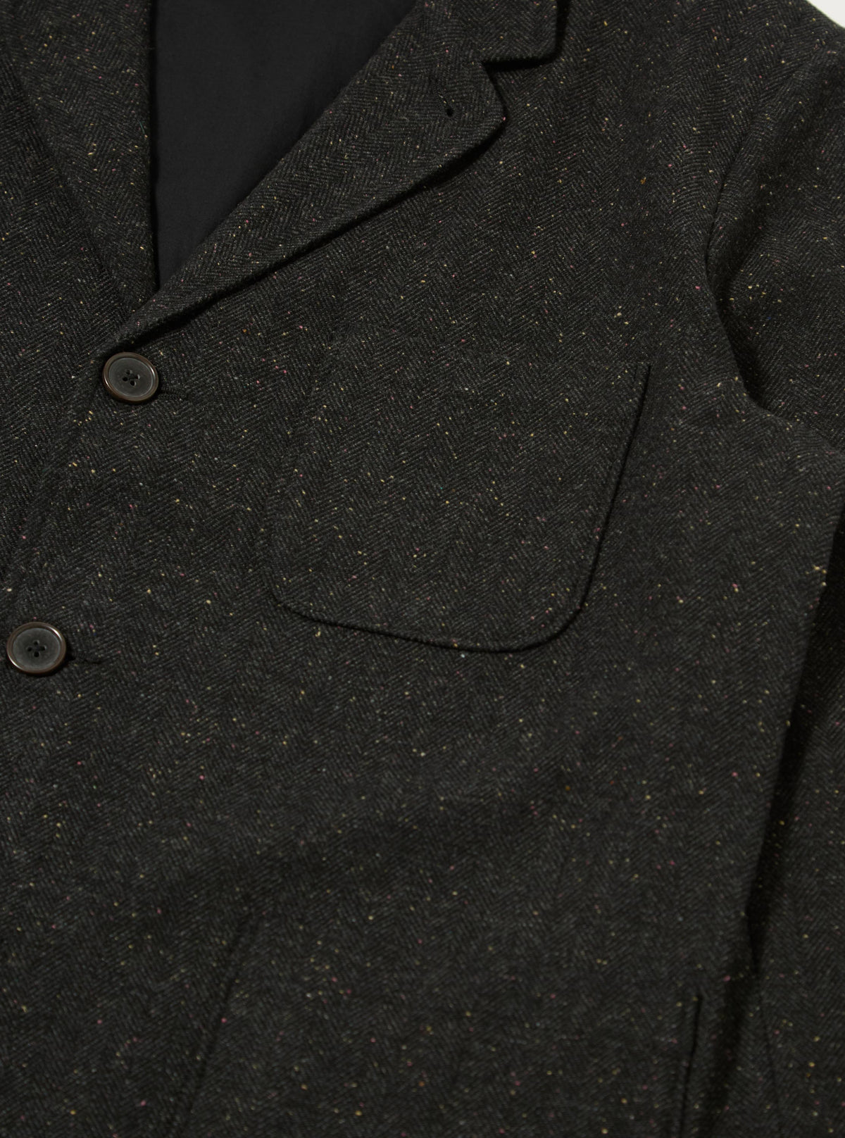 Close up of the Black Salt N Pepper Tweed Three Button Jacket. The tweed material is visible, along with the buttons and pocket. The background is a plain white.