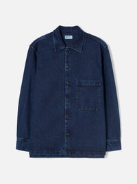 The Indigo Work Denim Fatigue Shirt is laid flat on a white studio backdrop. Features a pointed collar, six dark buttons down the front placket, a single chest patch pocket on the right, long sleeves with button cuffs, and a twill weave fabric.