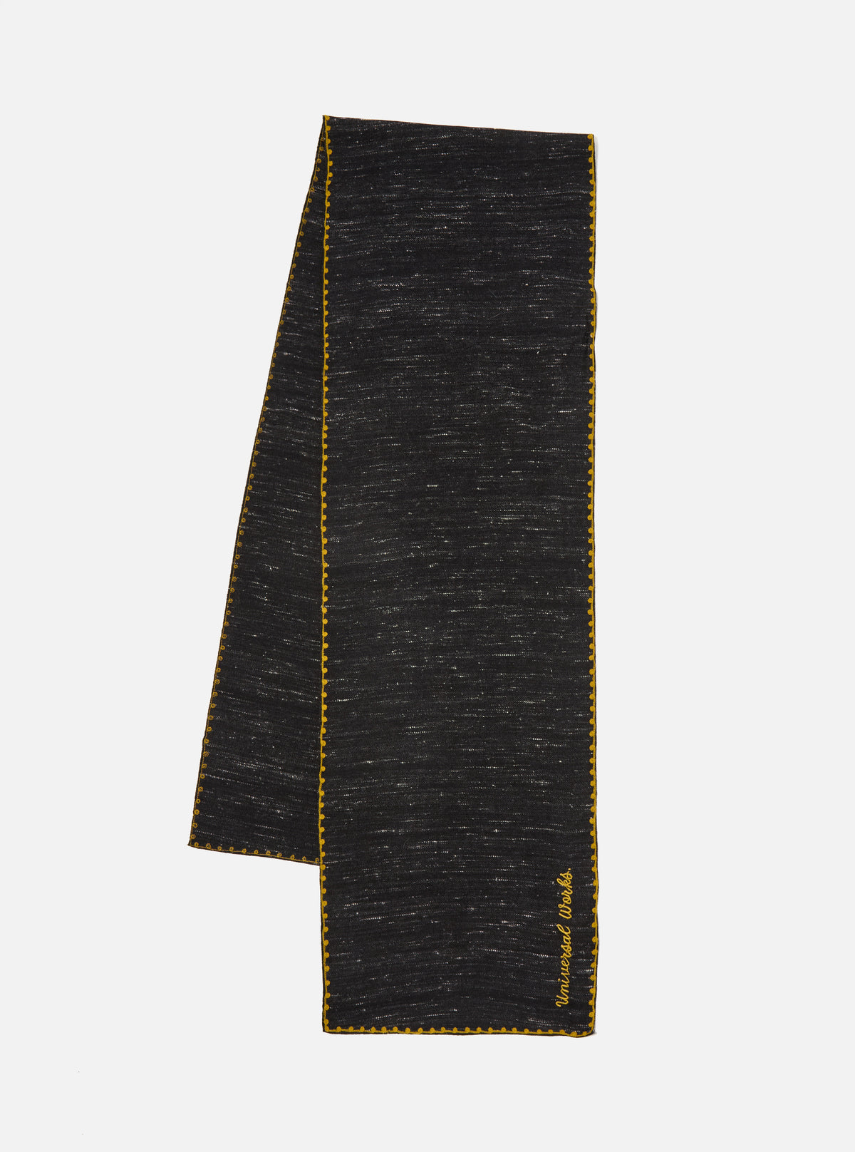 A black wool scarf with yellow trim is displayed on a white background. The Black Wool Scarf has the words 'Universal Works' embroidered on it.