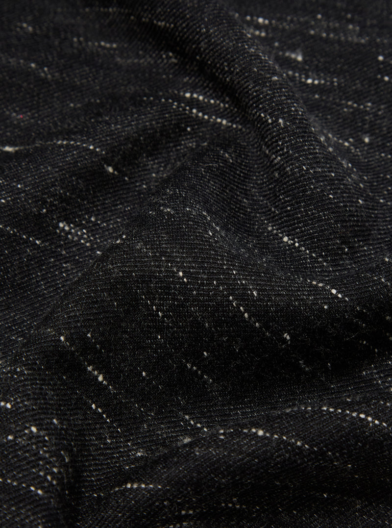 Close-up of a textured black wool scarf. The fabric has subtle white flecks. The Black Wool Scarf is draped to show its soft texture.