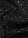 Close-up of a textured black wool scarf. The fabric has subtle white flecks. The Black Wool Scarf is draped to show its soft texture.