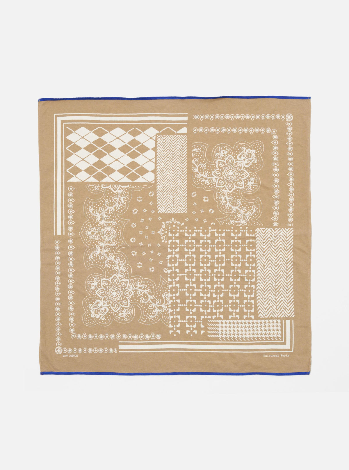 The Sand Single Jersey Neckerchief, a tan cotton square with white geometric and floral prints and a blue border, is laid flat on a white surface.
