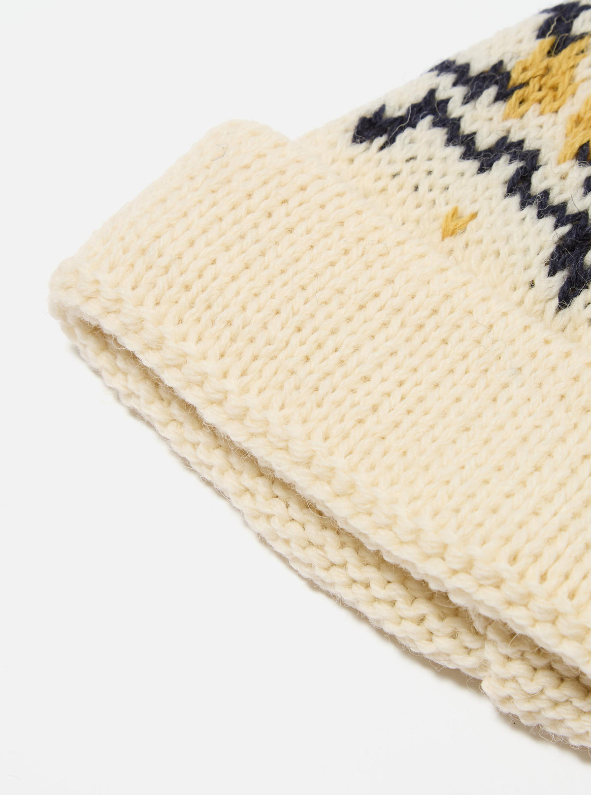 Close-up of an Ecru/Navy British Wool Short Watch Cap on a white background. The cap features a knit pattern with ecru, navy, and gold colors.