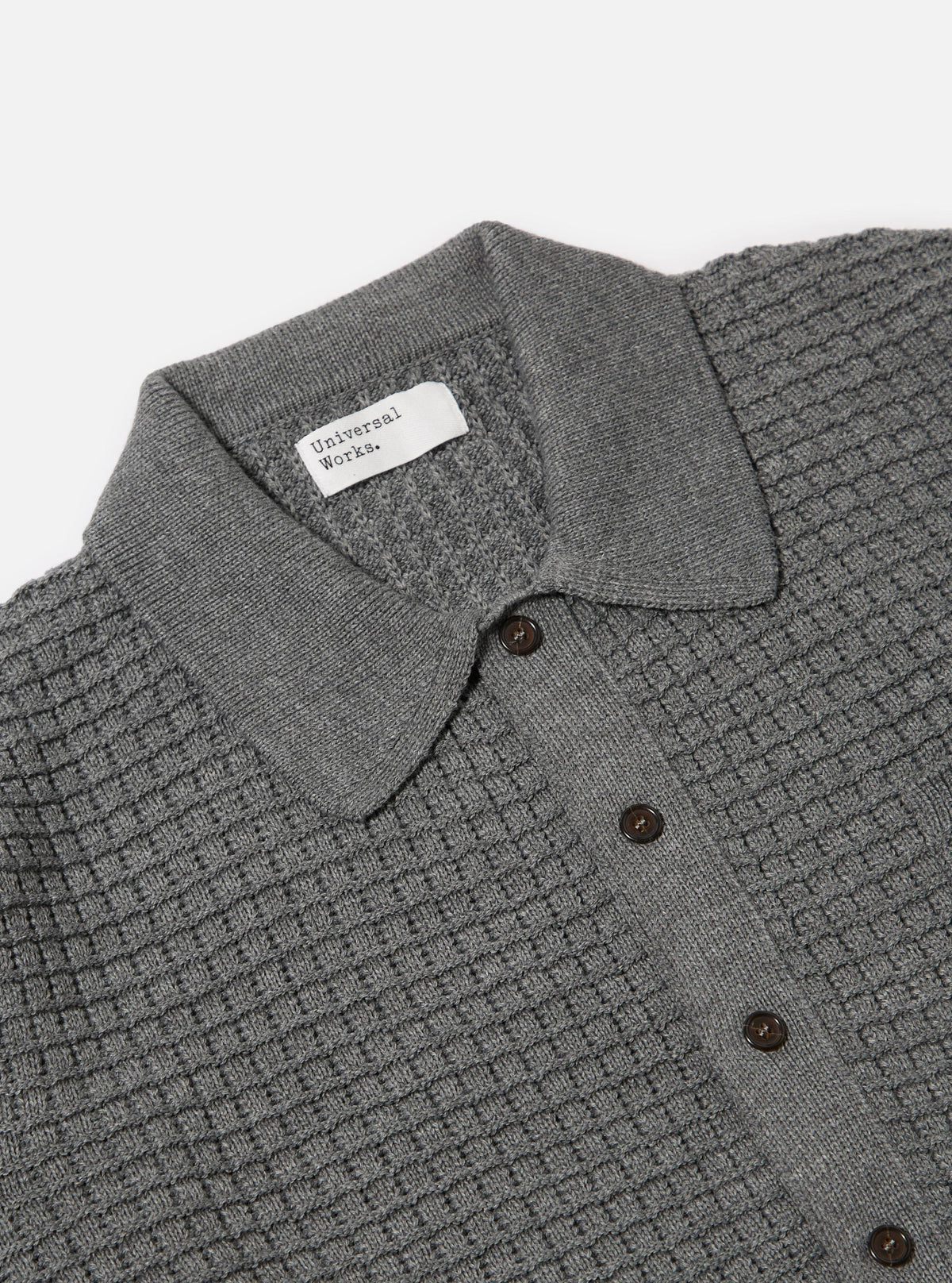 Close-up of the grey textured Merino knit Charlie Cardigan on a white background. The cardigan has a collared neck and brown buttons.