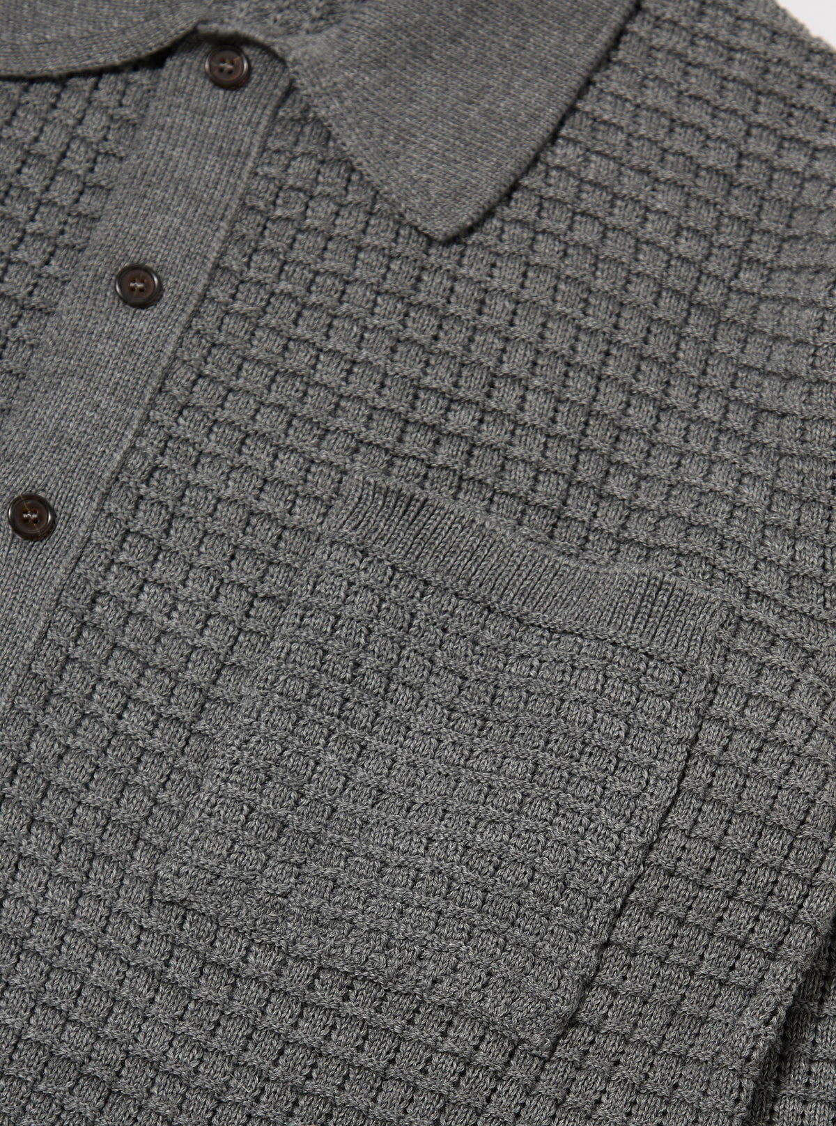 Close-up of the grey textured Merino knit Charlie Cardigan on a white background. Shows the knit detail, buttons, and pocket.