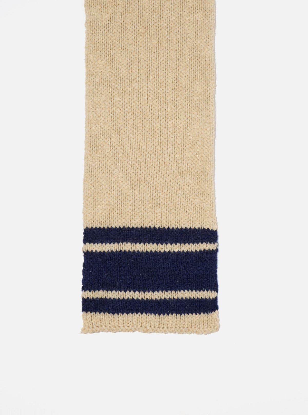 Close-up of a Sand Chunky Knit Stripe Lenny Scarf on a white background. The scarf is cream with navy blue stripes near the bottom.