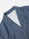Close-up of the Indigo Denim Herringbone Manor Jacket on a white surface. The jacket features a blue and white herringbone pattern and a light-colored lining.