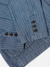 Close-up of the Indigo Denim Herringbone Manor Jacket showing the blue herringbone pattern, brown buttons, and tailored fit on a white background.