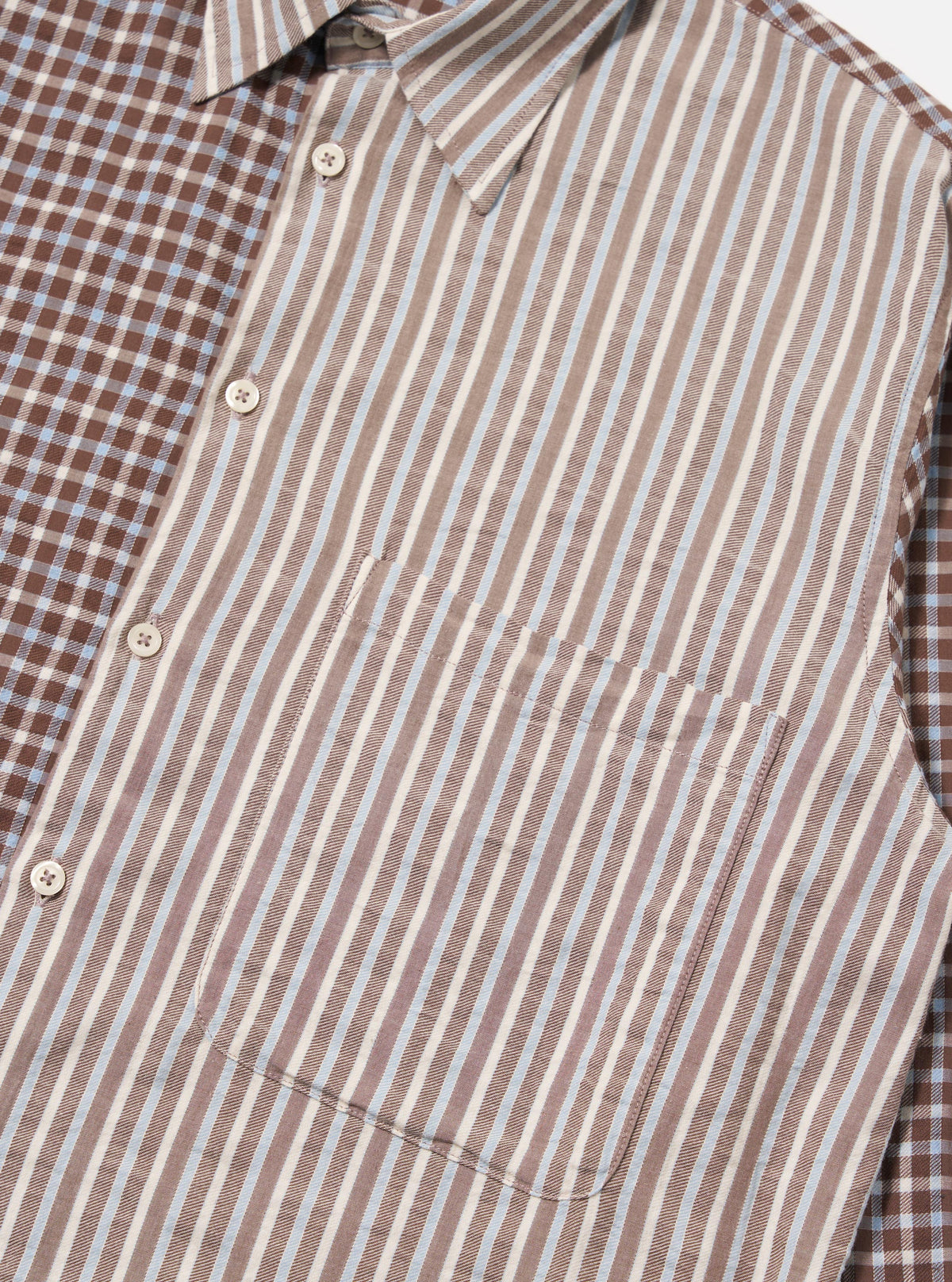 Close-up of the Brown Madison Check/Stripe Station Shirt. Features a brown and blue check pattern on one side and brown, white, and blue stripes on the other. White buttons. Pocket detail. 