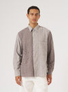 A model wears the Brown Madison Check/Stripe Station Shirt. The shirt is half brown check, half brown stripe. Shot in front of a white background.
