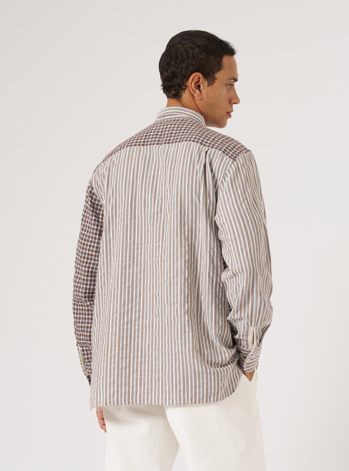 A man poses in the Brown Madison Check/Stripe Station Shirt against a white backdrop. The shirt features brown stripes and check patterns.
