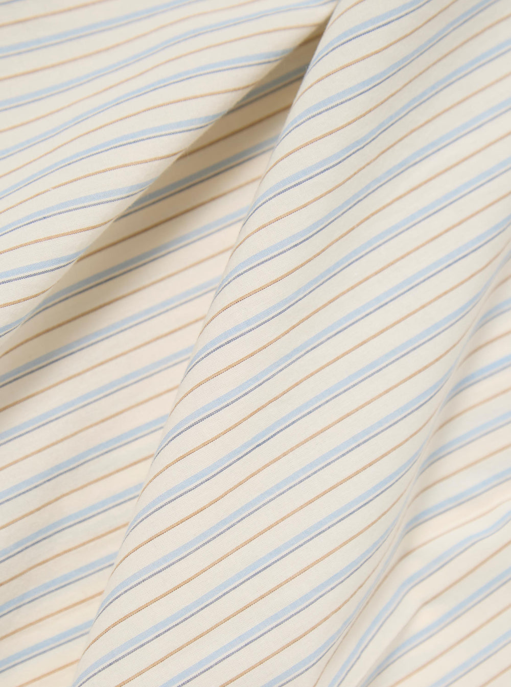 Close-up of the Ecru Pop Stripe One Lazy Day Shirt fabric. Features ecru, light blue, and tan stripes. The material is draped on a plain surface.