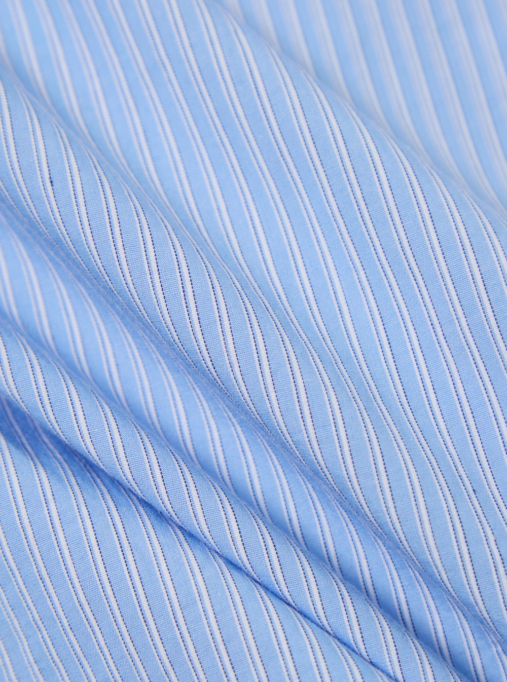 Close-up of the Blue Vila Stripe Narrow Lazy Day Shirt fabric. Light blue with thin white stripes. Soft, draped cotton material.