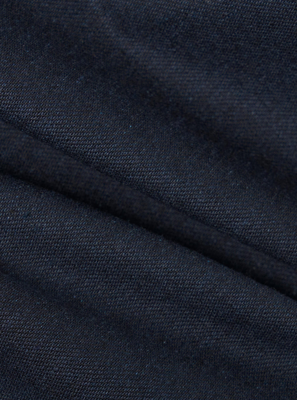 Close-up of the Navy Lucca Suiting Military Chino fabric. The dark blue material is textured and folded, showcasing its quality.