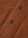 A close-up view of the Cumin Alvar Fleece Lancaster Jacket worn by a model against a clean studio backdrop. The shot emphasizes the textured recycled fleece fabric, patch pockets, button closure, and jersey-bound edges.