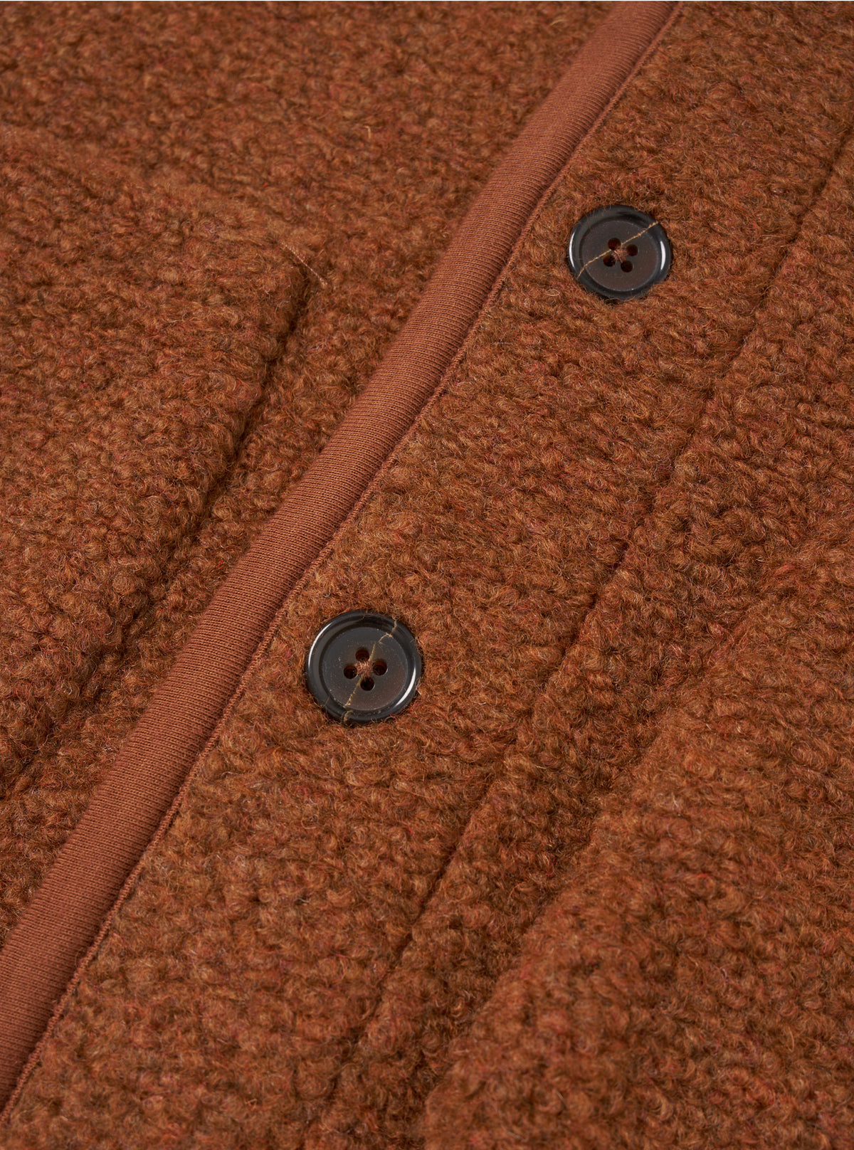 A close-up view of the Cumin Alvar Fleece Lancaster Jacket worn by a model against a clean studio backdrop. The shot emphasizes the textured recycled fleece fabric, patch pockets, button closure, and jersey-bound edges.