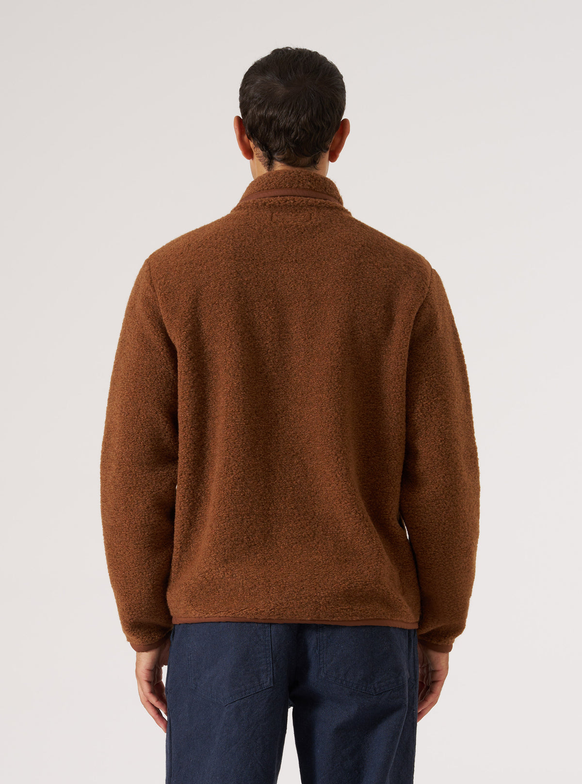 Back view of a model in a Cumin Alvar Fleece Lancaster Jacket. The jacket is brown fleece. Shot against a white background.