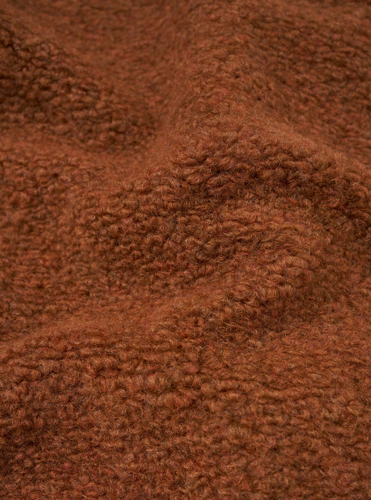 A macro close-up fabric swatch image of the Cumin Alvar Fleece Lancaster Jacket displayed against a plain background. The shot focuses on the textured, plush cumin-colored fleece knit, highlighting its rich wool blend structure.