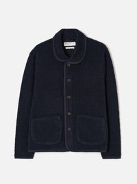 A male model stands against a plain neutral studio background wearing the Navy Alvar Fleece Lancaster Jacket. The front-view image displays the deep navy blue shade, cozy shawl collar, front button closure, and two patch pockets.