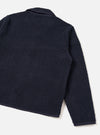 A male model wears the Navy Alvar Fleece Lancaster Jacket shown from a three-quarter angle against a light studio backdrop. The shot highlights the relaxed fit, soft recycled wool-blend fleece texture, and jersey-trimmed cuffs.