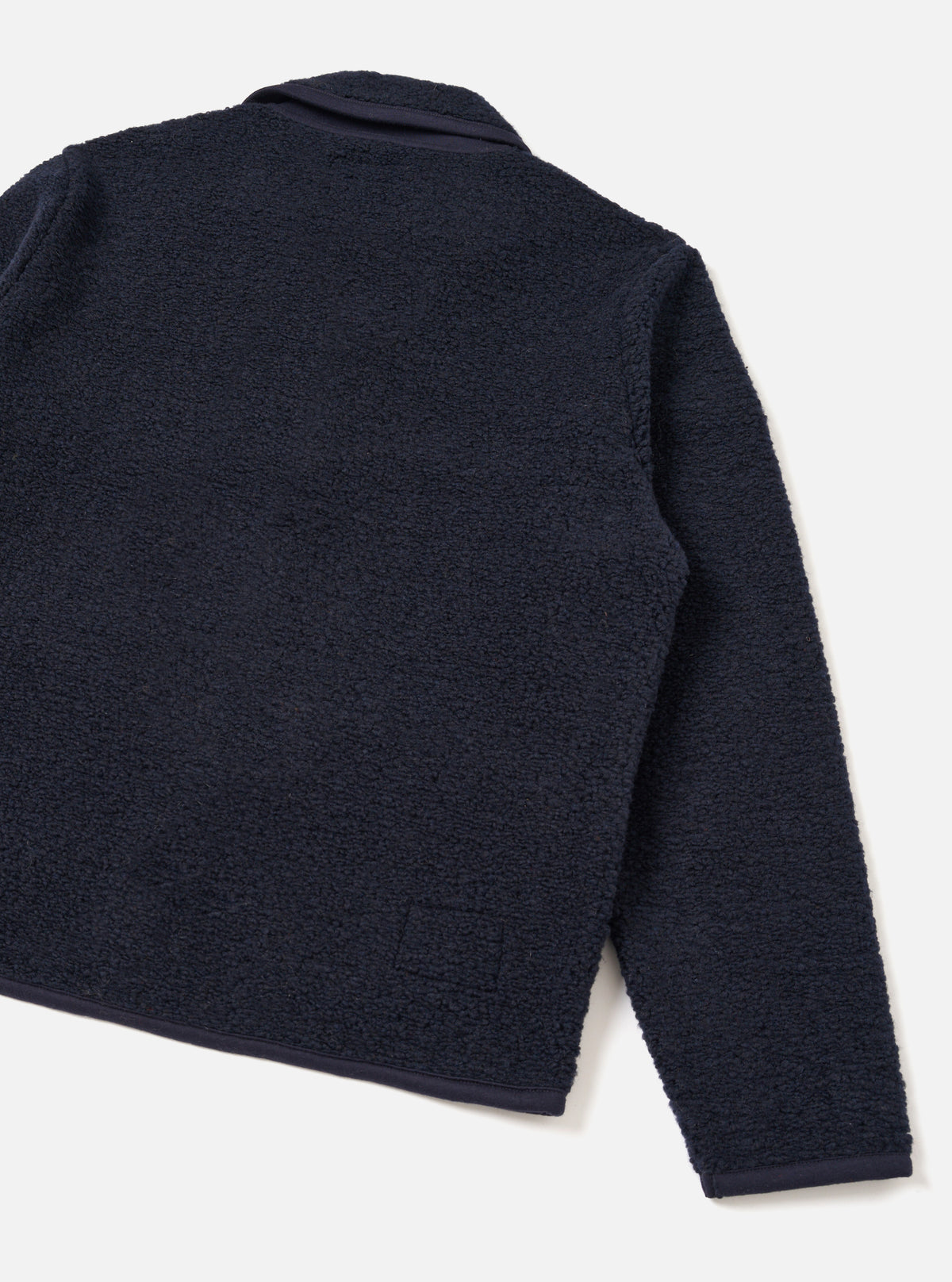 A male model wears the Navy Alvar Fleece Lancaster Jacket shown from a three-quarter angle against a light studio backdrop. The shot highlights the relaxed fit, soft recycled wool-blend fleece texture, and jersey-trimmed cuffs.