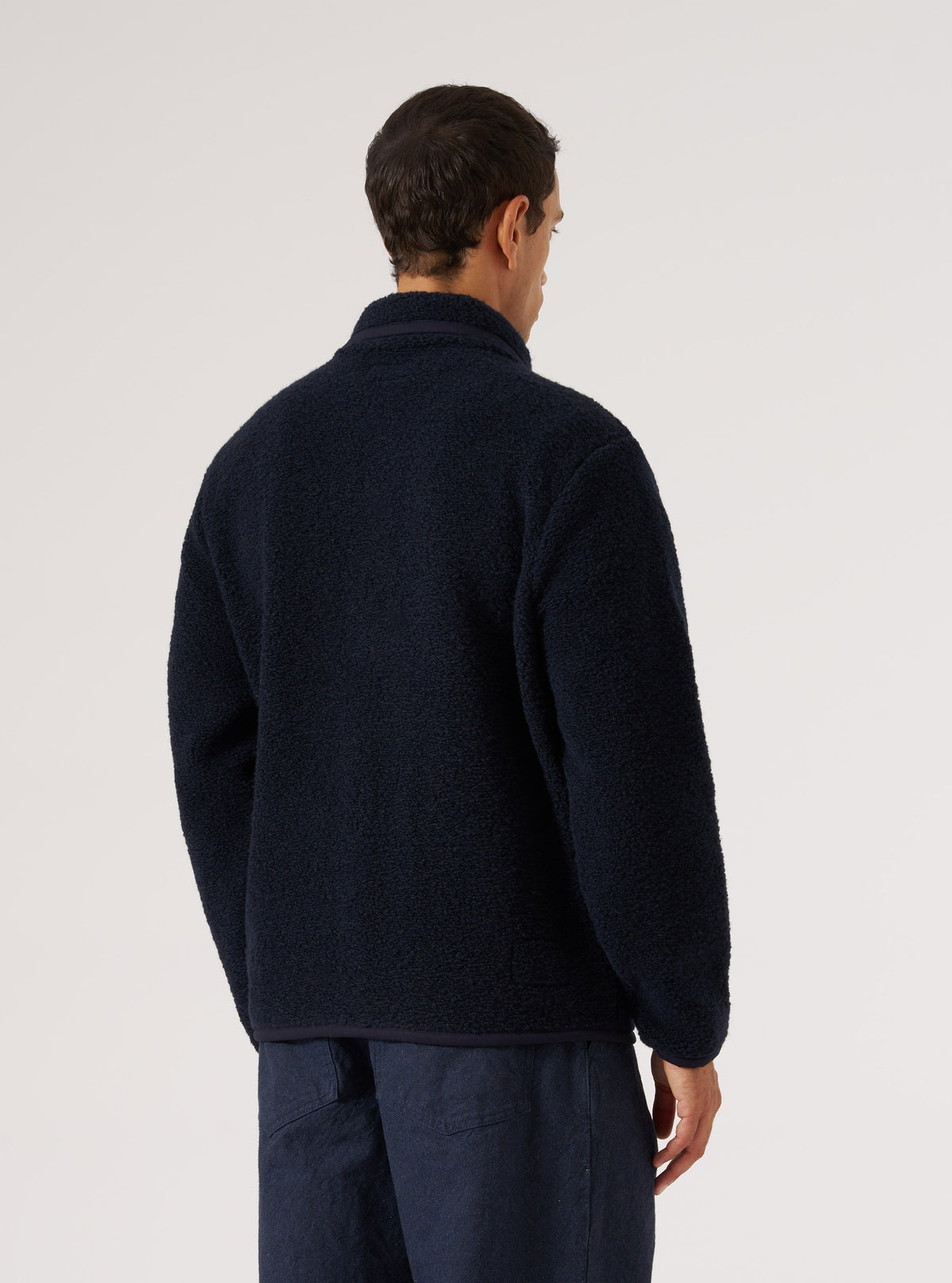 Back view of a man wearing the Navy Alvar Fleece Lancaster Jacket. The jacket is fleece and the background is a plain white.