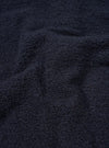 A close-up fabric swatch photograph of the Navy Alvar Fleece Lancaster Jacket against a plain neutral background. The detail image showcases the soft, looped weave and plush textured pile of the dark navy recycled wool fleece.