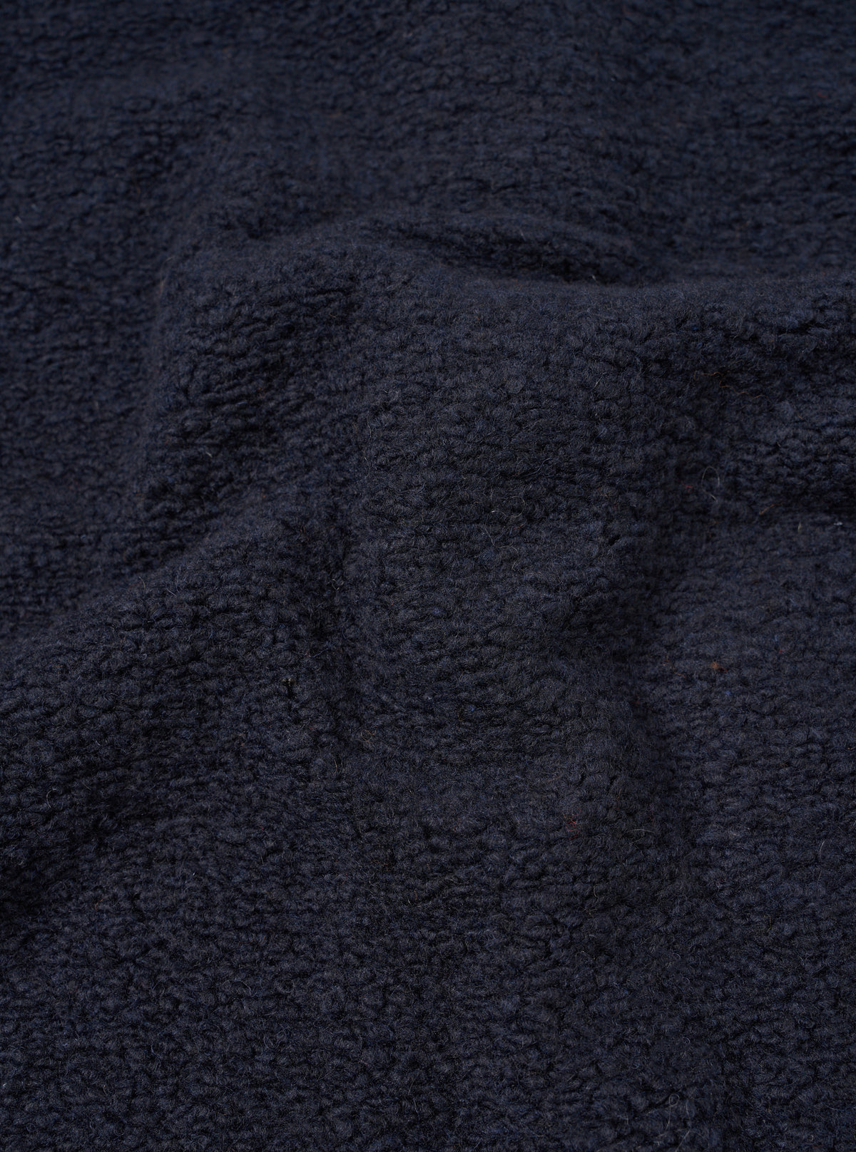 A close-up fabric swatch photograph of the Navy Alvar Fleece Lancaster Jacket against a plain neutral background. The detail image showcases the soft, looped weave and plush textured pile of the dark navy recycled wool fleece.