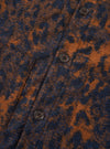 A close-up view of the Dark Navy/Brown Night Leopard Cardigan worn by a model in a studio setting. The photograph emphasizes the custom leopard pattern texture, self-bound placket with tonal buttons, and rib-bound hem detailing.