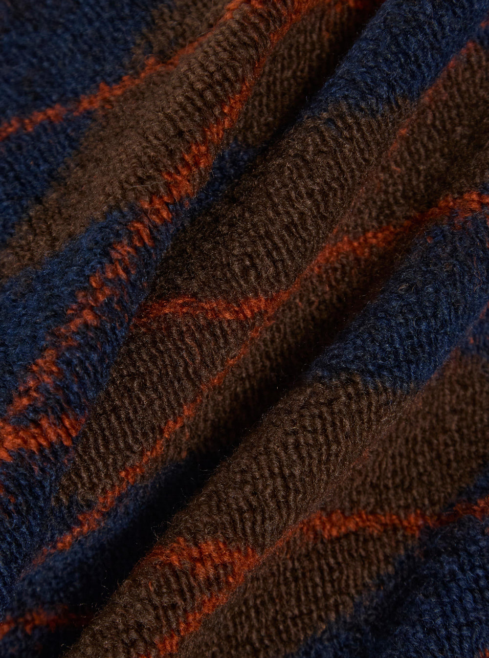 Close-up of the Brown/Navy Argyll Fleece Sleeveless Crew fabric. The fleece has a brown and navy argyll pattern with orange stripes. 