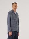 A man stands in front of a white background, wearing a Navy Oscar Cotton L/S Camp Shirt. The shirt has a blue, white, and brown geometric pattern. The fit is relaxed.