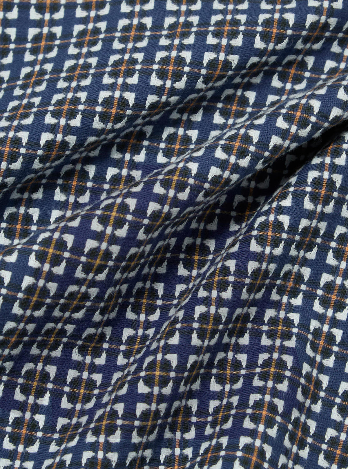 Close-up of the Navy Oscar Cotton L/S Camp Shirt fabric. The shirt features a navy background with a white, black, and orange pattern. The cotton fabric is soft and slightly wrinkled.