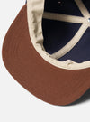 Close-up of the inside of a Navy/Brown Canvas Baseball Hat. The hat has a brown brim, navy canvas, and brown canvas lining. Shot on a white background.
