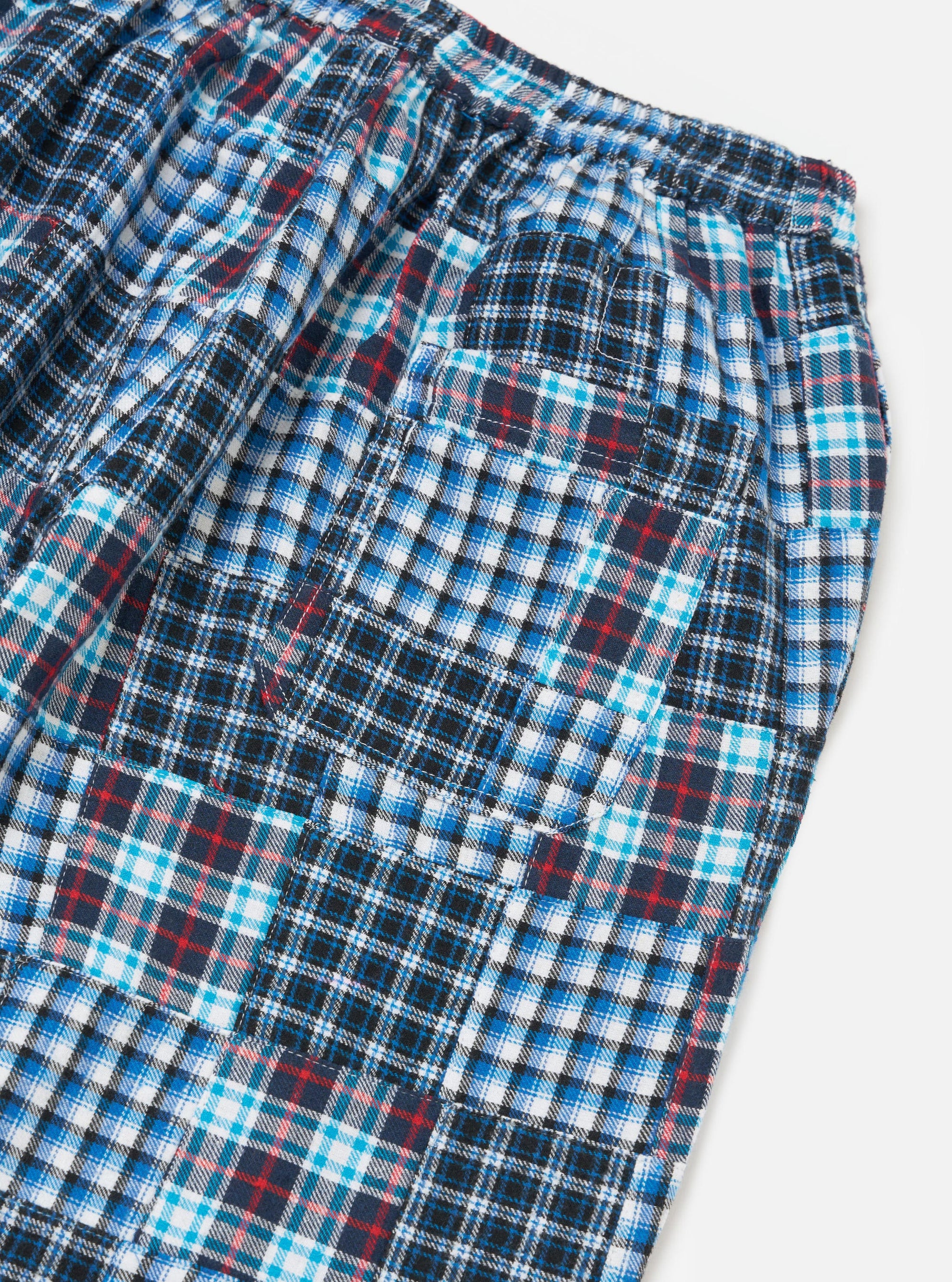 Close-up of the Blue Brushed Patchwork Pyjama Pant on a white surface. The brushed cotton pants feature a blue, white, and red patchwork plaid pattern.