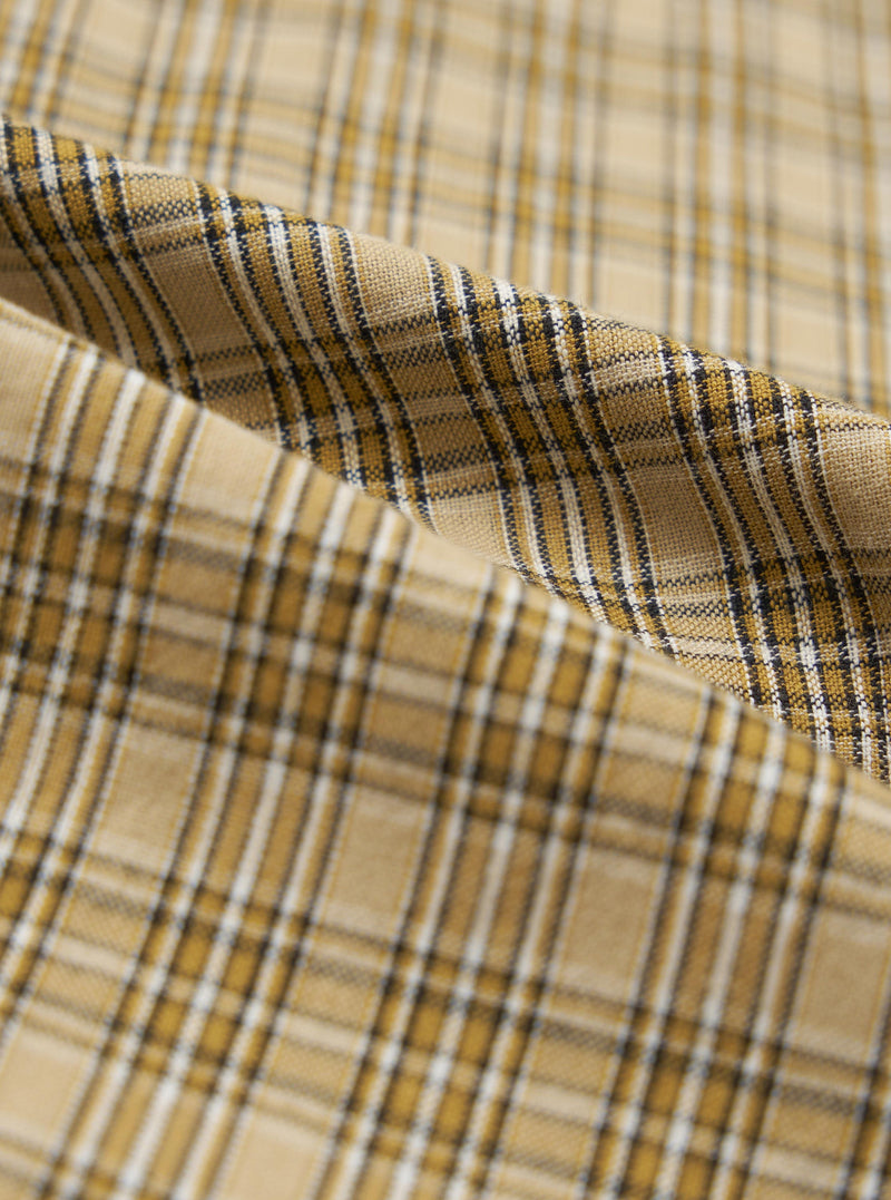Close-up of the Sand Picnic Plaid Pyjama Pant fabric. The material is a soft, woven plaid in shades of sand, gold, white, and black. The fabric is draped to show texture.