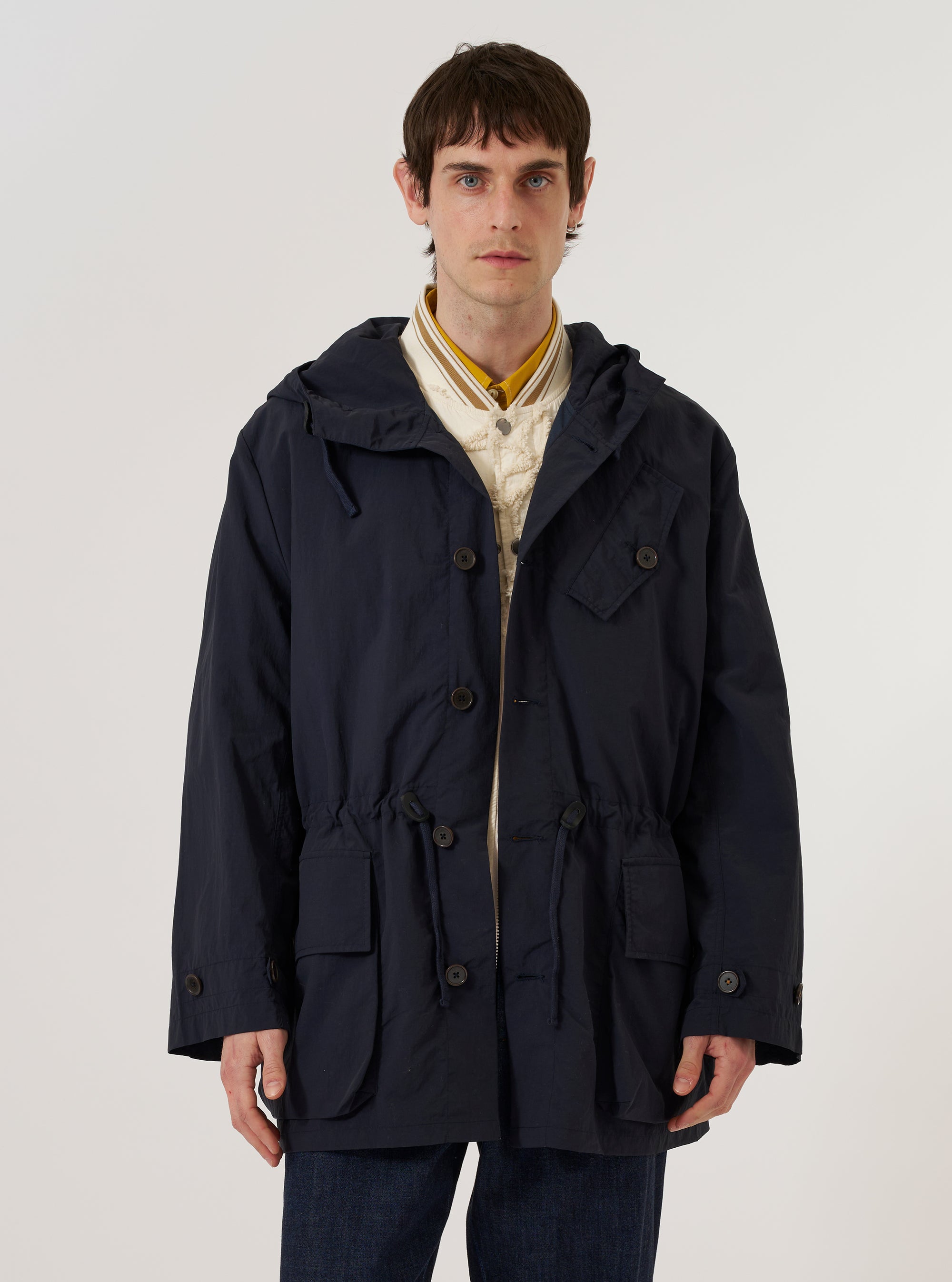A model wears the Navy Seo Recycled Nylon Boston Parka against a plain white background. The parka features an oversized fit, a large hood, and two prominent front flap pockets with button closures.