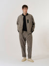 The Grey Brown Wales Glen Check NS Bomber Jacket is shown as a flat lay against a white background. The jacket features a subtle glen check pattern in shades of grey and brown, a full zip front, a ribbed collar, and elasticated cuffs and hem. Two slanted welt pockets are visible at the sides.
