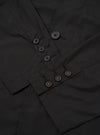 The Black Recycled Polytech Capitol Jacket is shown in a close-up detail shot as a flat lay against a plain white background. The image focuses on the lower front section of the garment, highlighting a large patch pocket with a flap closure and the smooth, technical texture of the black recycled polytech fabric. Clean tonal stitching and a straight hem are visible.