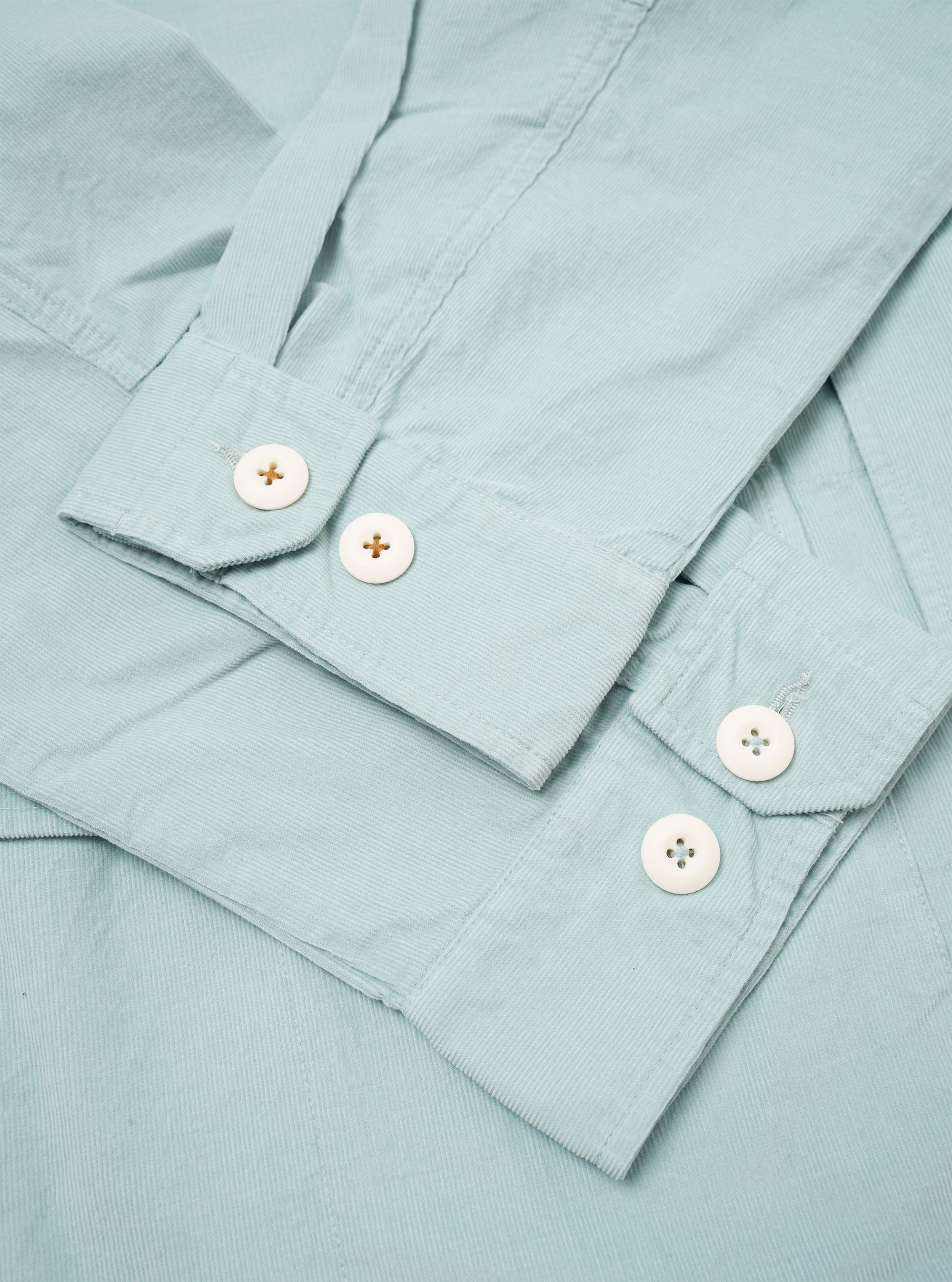 The Aqua Organic Fine Cord Duty Jacket is presented as a flat lay against a plain white background. The jacket features a structured collar, a button-front closure, and three large patch pockets on the front. The fine-ribbed texture of the aqua-colored organic cotton corduroy is clearly visible.