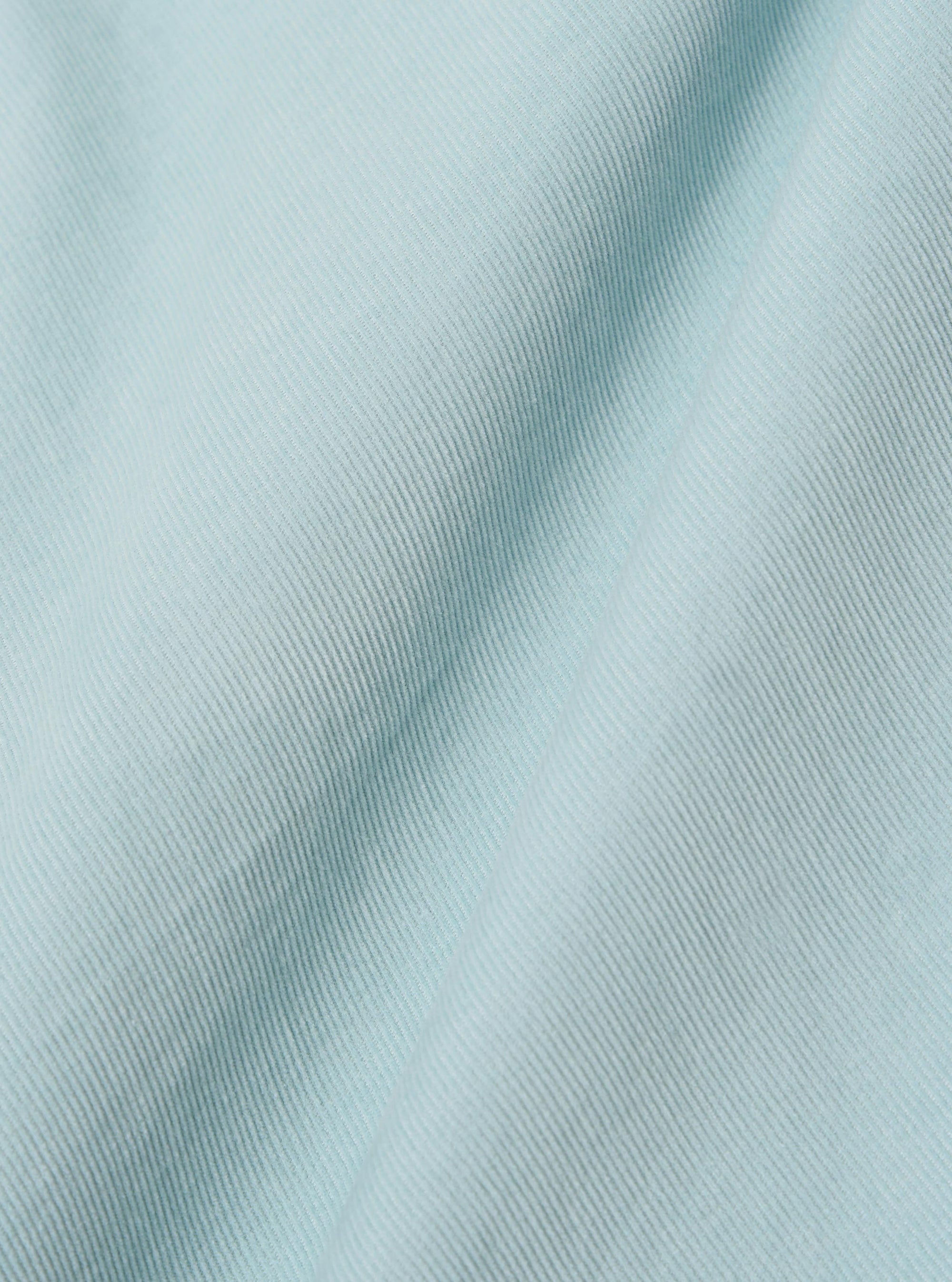 A close-up swatch image of the Aqua Organic Fine Cord Duty Jacket fabric shows the fine-ribbed corduroy texture in a bright aqua blue color. The image focuses on the detail of the organic cotton material, highlighting the consistent vertical lines of the cord.
