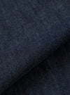 A close-up fabric swatch of the Indigo Kaihara LT WT Denim Labour Jacket highlights the deep indigo blue color and the fine, lightweight weave of the Japanese denim. The textile fills the frame, showcasing a uniform color and smooth surface.
