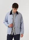 A model wears the Navy Kennedy Stripe Labour Jacket while standing against a plain white background. The jacket features a vertical navy and white stripe pattern, a classic collar, a single chest patch pocket, and two large lower patch pockets. The model is shown from the waist up, highlighting the garment's fit and texture.
